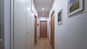 A narrow hallway with white walls, wooden doors, and tiled flooring. - Casa Rosa Beige e Blu (Rome)