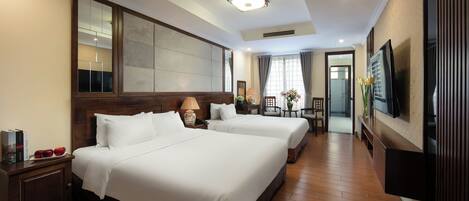 A hotel room with two beds, a TV, a wooden floor, and a large mirror.