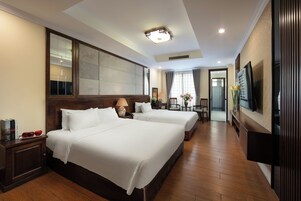 Een hotelkamer met twee bedden, een televisie, een houten vloer en een grote spiegel.