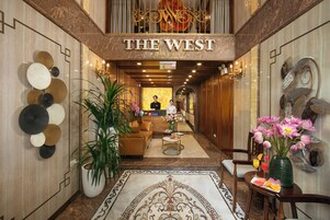 A hotel lobby with a reception desk, a seating area, and a decorative wall with circular patterns.