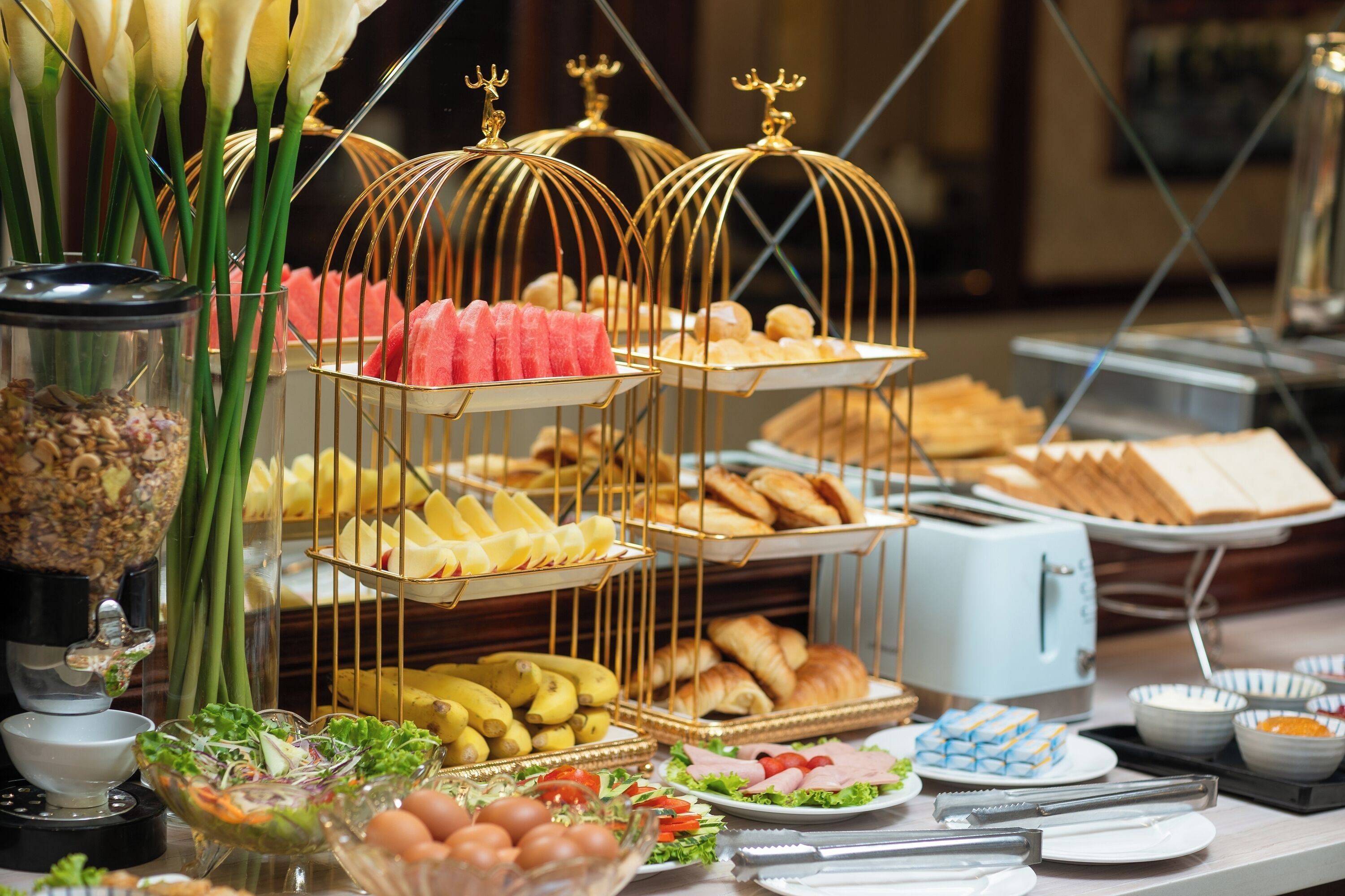 A buffet table with various food items, including fruits, pastries, and salads.