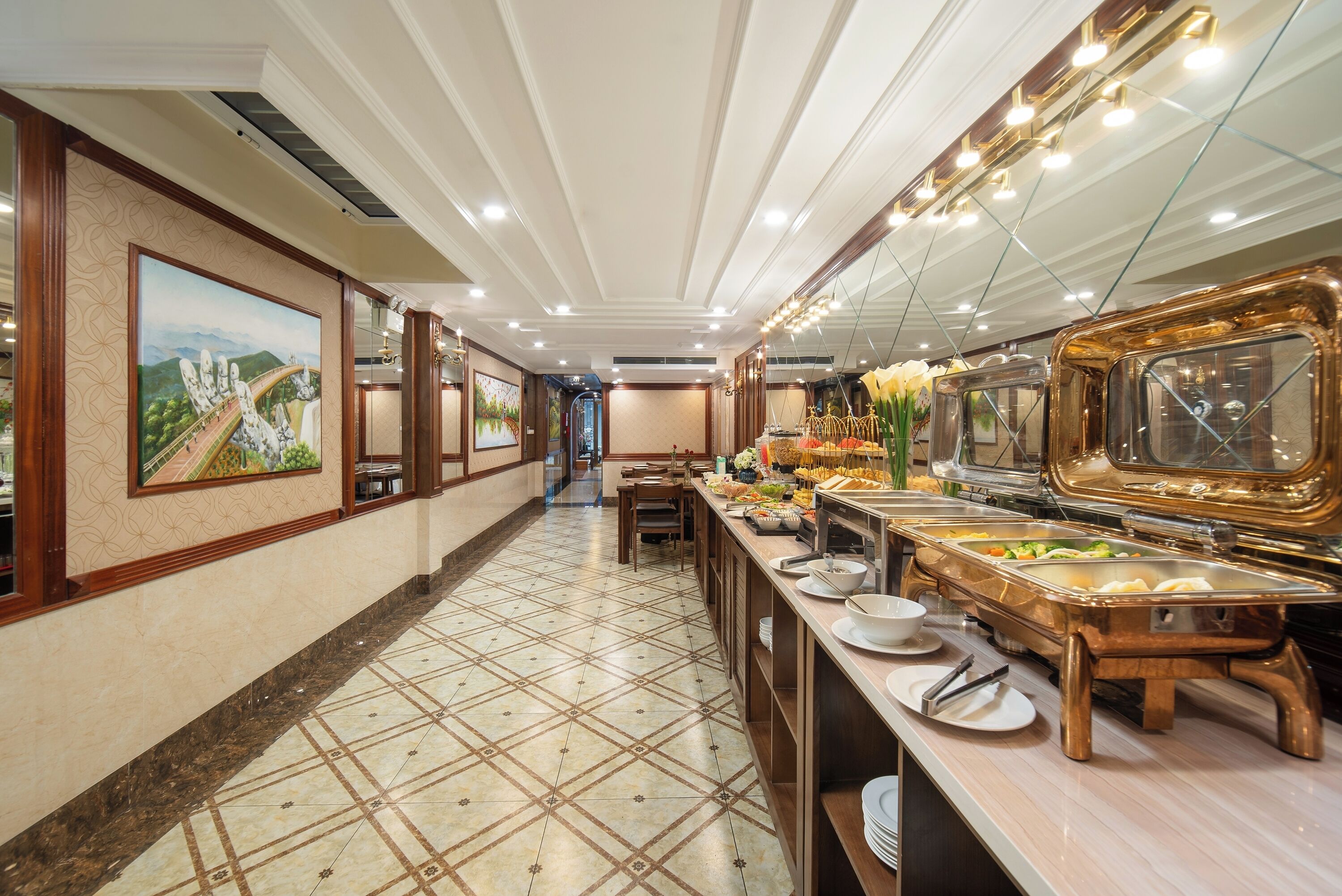 Un couloir d’hôtel avec un espace buffet proposant une variété de plats, un coin salon et des œuvres d’art accrochées aux murs.