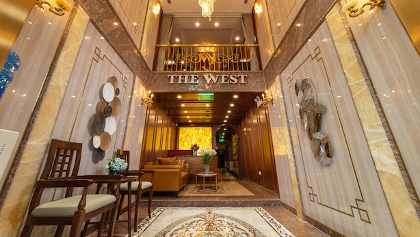A luxurious lobby with a chandelier, a reception desk, and a sign reading "THE WEST". - The West Hotel & Spa (Hanoi)