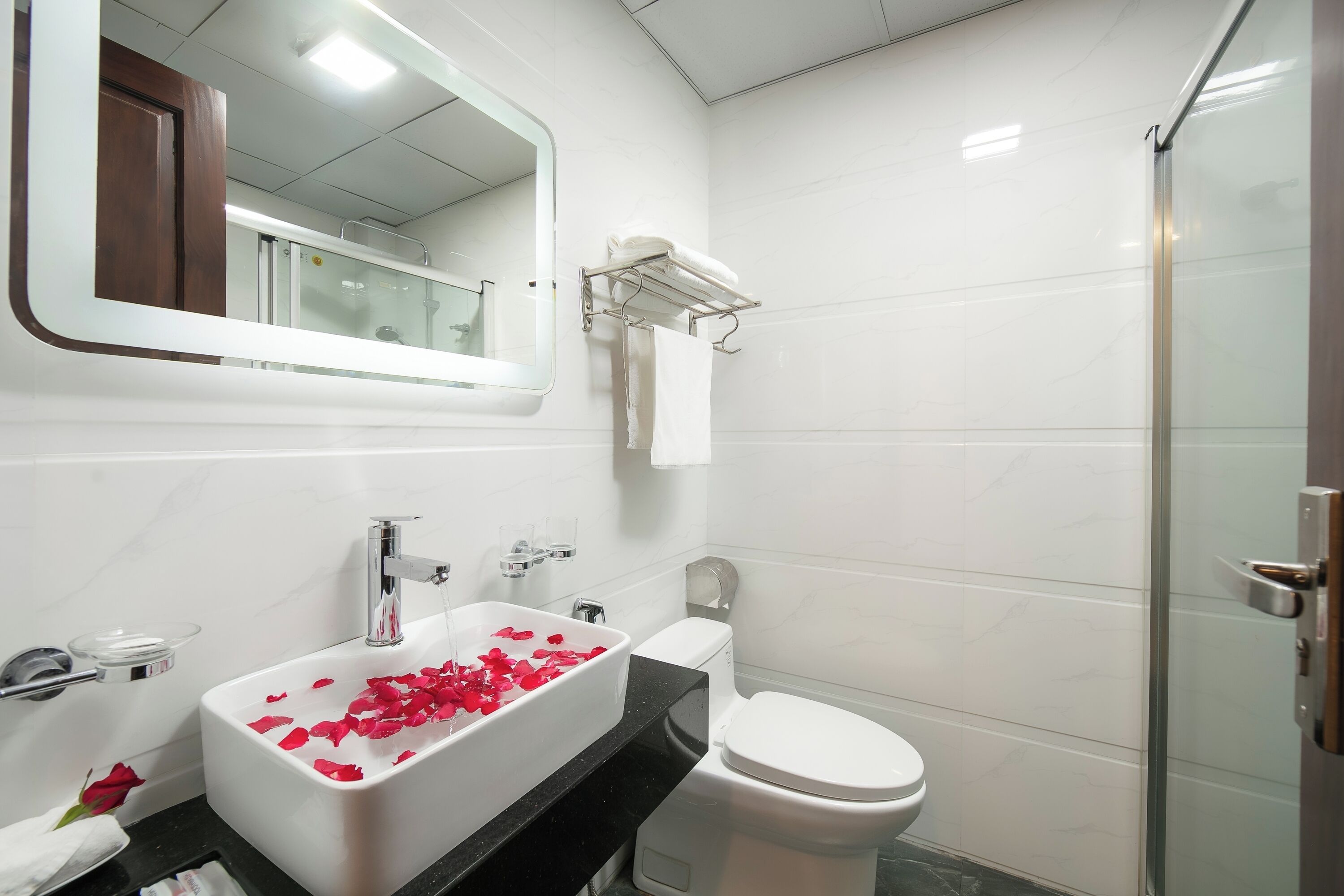 Un baño con lavamanos blanco, espejo, inodoro y zona de ducha.