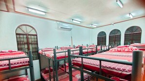 A dormitory room with bunk beds, a window, and an air conditioning unit. - Mang Ben Dormitory - Kaliraya QC - Hostel (Quezon City)
