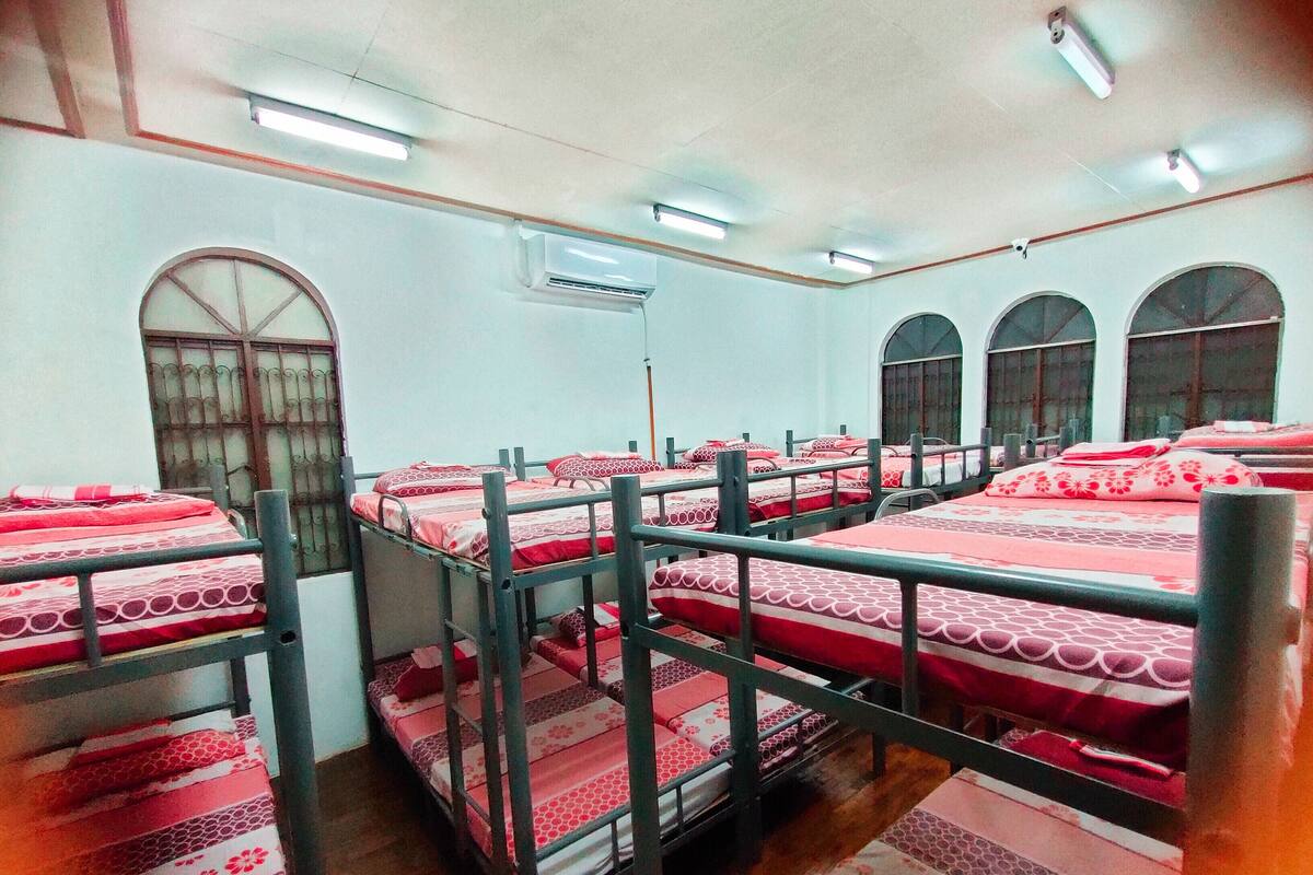 Een studentenkamer met stapelbedden, een raam en een airconditioner.
