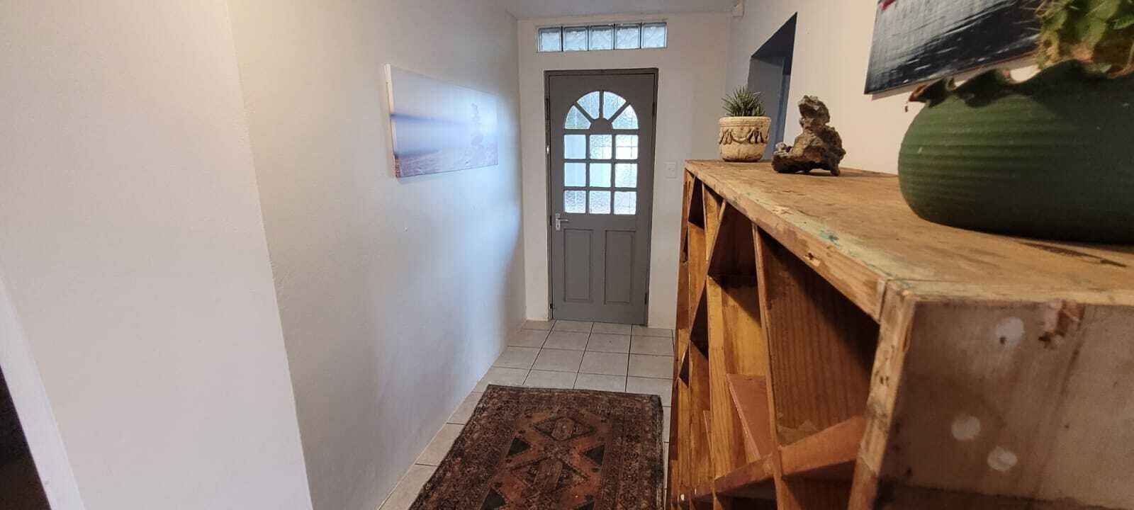 A hallway with a wooden bench, a potted plant, and a door with a window.