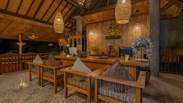 Un interior de madera con un mostrador de recepción, zona de estar y elementos decorativos.