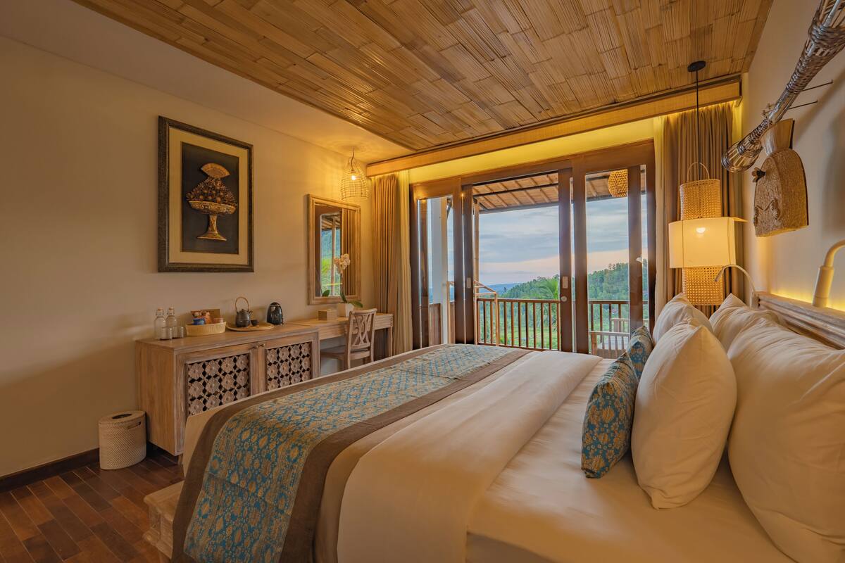 A hotel room with a large bed, a desk, and a view of the outdoors.