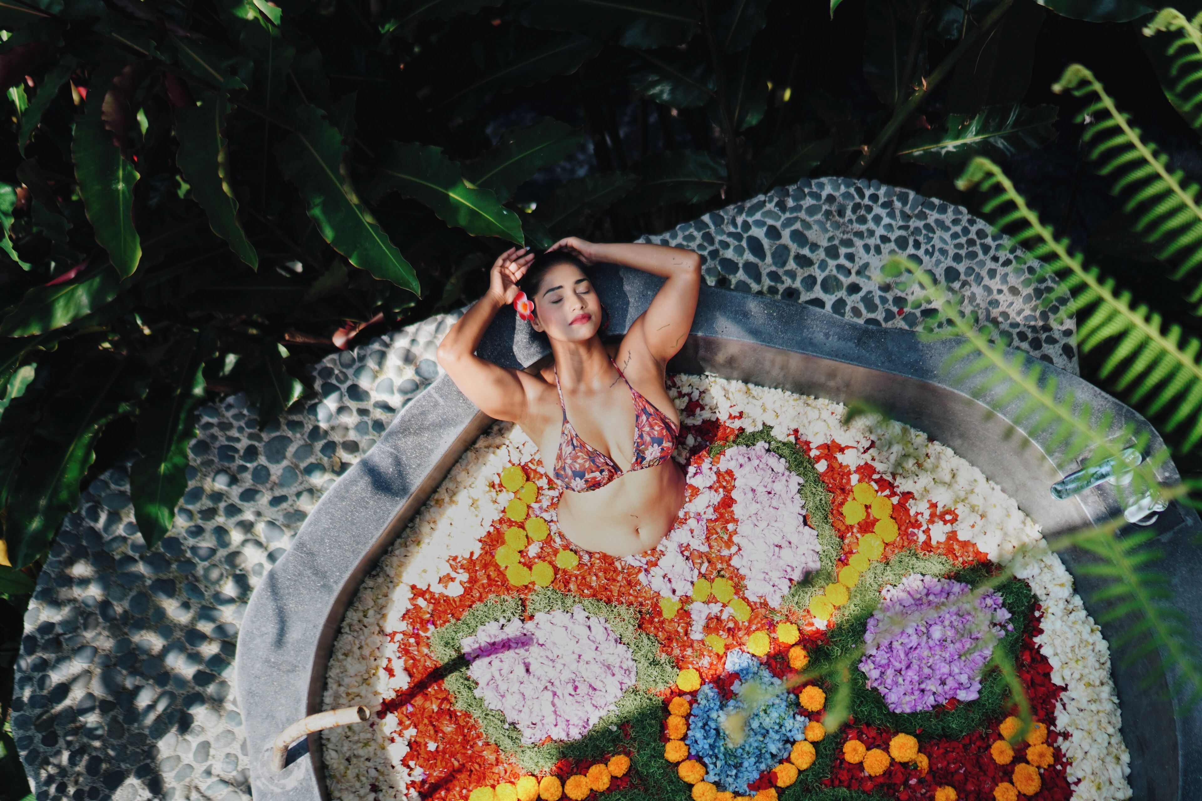 Une personne allongée sur un lit de pétales de fleurs multicolores.