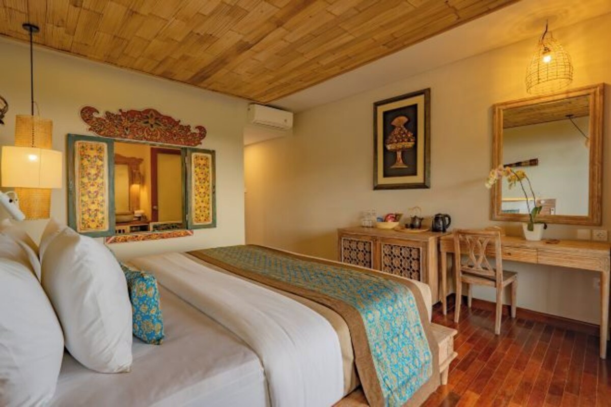 Un dormitorio con cama, mesita de noche, silla, escritorio y espejo.
