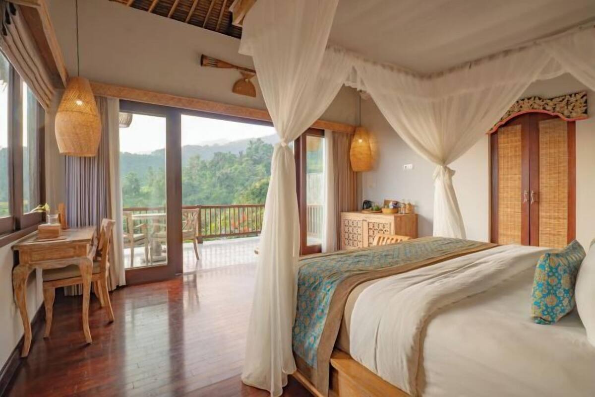 A bedroom with a large bed, a balcony, and a dining area.