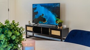 A television on a black stand with a scenic image on the screen, a small plant, and a candle on the table. - LOVELY STAY |GREAT LOCATION NEAR DISNEY & DOWNTOWN (Fullerton)