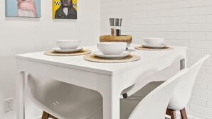 A modern dining area with a white table and chairs, artwork on the wall, and a wooden floor. - Lovely 1-bedroom condo in Baltimore - Parking (Phoenix)