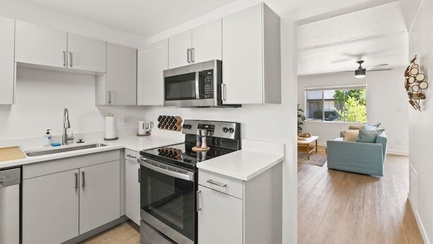A modern kitchen with white cabinetry, a stainless steel stove, and a microwave. - Lovely 1-bedroom condo in Baltimore - Parking (Phoenix)
