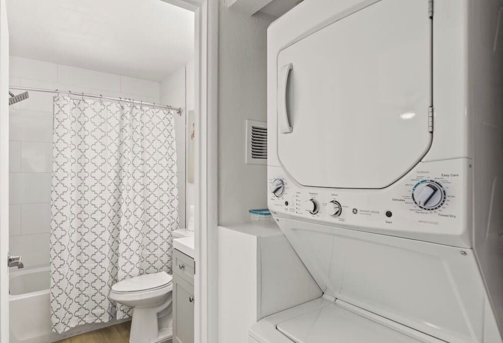Une salle de bain moderne équipée d’une douche, de toilettes et d’un lave-linge à chargement frontal.