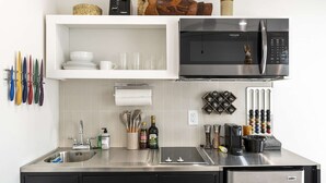 A modern kitchen with a stainless steel refrigerator, a microwave, and a built-in oven. There are utensils hanging on the wall, a sink with a faucet, and a countertop with a bottle of olive oil and a bottle of wine. - Hinny's sweet suite w/ Heated Pool, GYM & Hot Tub (Scottsdale)