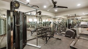 Un gimnasio con diversos equipos de ejercicio, como mancuernas, cintas de correr y máquinas de pesas.