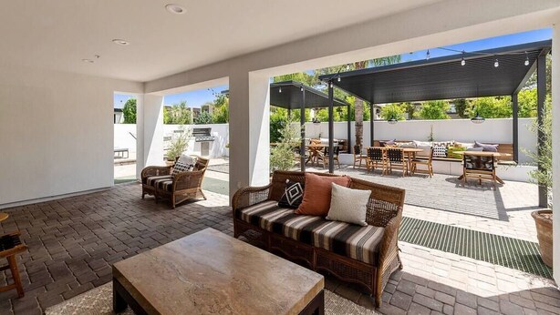An open-plan living area with a sofa set, a coffee table, and a dining area with outdoor seating. - Cuddy's sweet suite W/ Heated Pool, GYM & Hot Tub (Scottsdale)