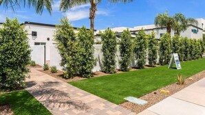 A modern building with a well-maintained lawn and palm trees. - Cuddy's sweet suite W/ Heated Pool, GYM & Hot Tub (Scottsdale)