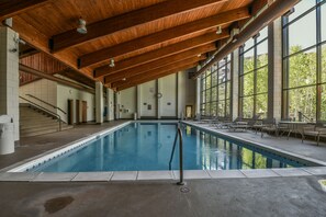 An indoor swimming pool with a wooden ceiling, large windows, and a staircase on the left. - Pines 2129 (Keystone)
