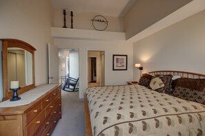 A bedroom with a large bed, a dresser, a mirror, and a framed picture on the wall. - Pines 2129 (Keystone)