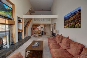 A spacious living area with a fireplace, a large flat-screen TV, and a cozy red sofa. - Pines 2129 (Keystone)