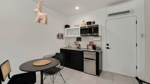 A compact kitchen with a dining area, featuring a black and white color scheme, a hanging giraffe ornament, and a modern design. - Neddy's sweet suite W/ Heated Pool, GYM & Hot Tub (Scottsdale)