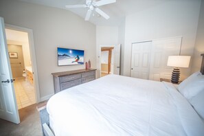 A bedroom with a large bed, a ceiling fan, a painting on the wall, and a door leading to another room. - Starfire 1990 (Keystone)