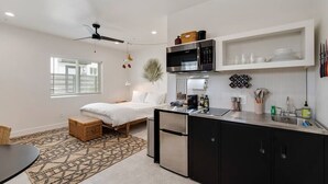 A compact kitchen with a refrigerator, microwave, and sink. There is a bed with a white comforter and a small table. - Burro's sweet suite W/ Heated Pool, GYM & Hot Tub (Scottsdale)