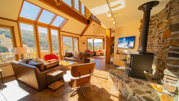 A spacious living room with a stone fireplace, large windows, and a cozy seating area. - Keystone Brom House 48 (Keystone)