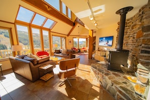 A spacious living room with a stone fireplace, large windows, and a cozy seating area. - Keystone Brom House 48 (Keystone)