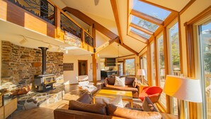 A spacious living area with a stone fireplace, leather sofas, and large windows offering views of the outdoors. - Keystone Brom House 48 (Keystone)