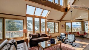 A spacious living room with a large window overlooking a mountainous landscape, a leather sofa, a glass coffee table, and modern chairs. - Keystone Brom House 48 (Keystone)