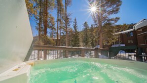 A hot tub surrounded by trees and a building with a snow-covered roof. - Starfire 1992 (Keystone)