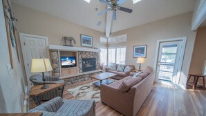 A spacious living room with a stone fireplace, comfortable seating, and a television. - Starfire 1992 (Keystone)