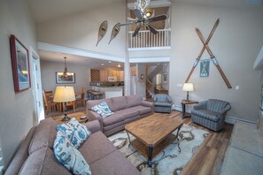 A spacious living room with a high ceiling, a wooden coffee table, a sofa, and a patterned rug. - Starfire 1992 (Keystone)