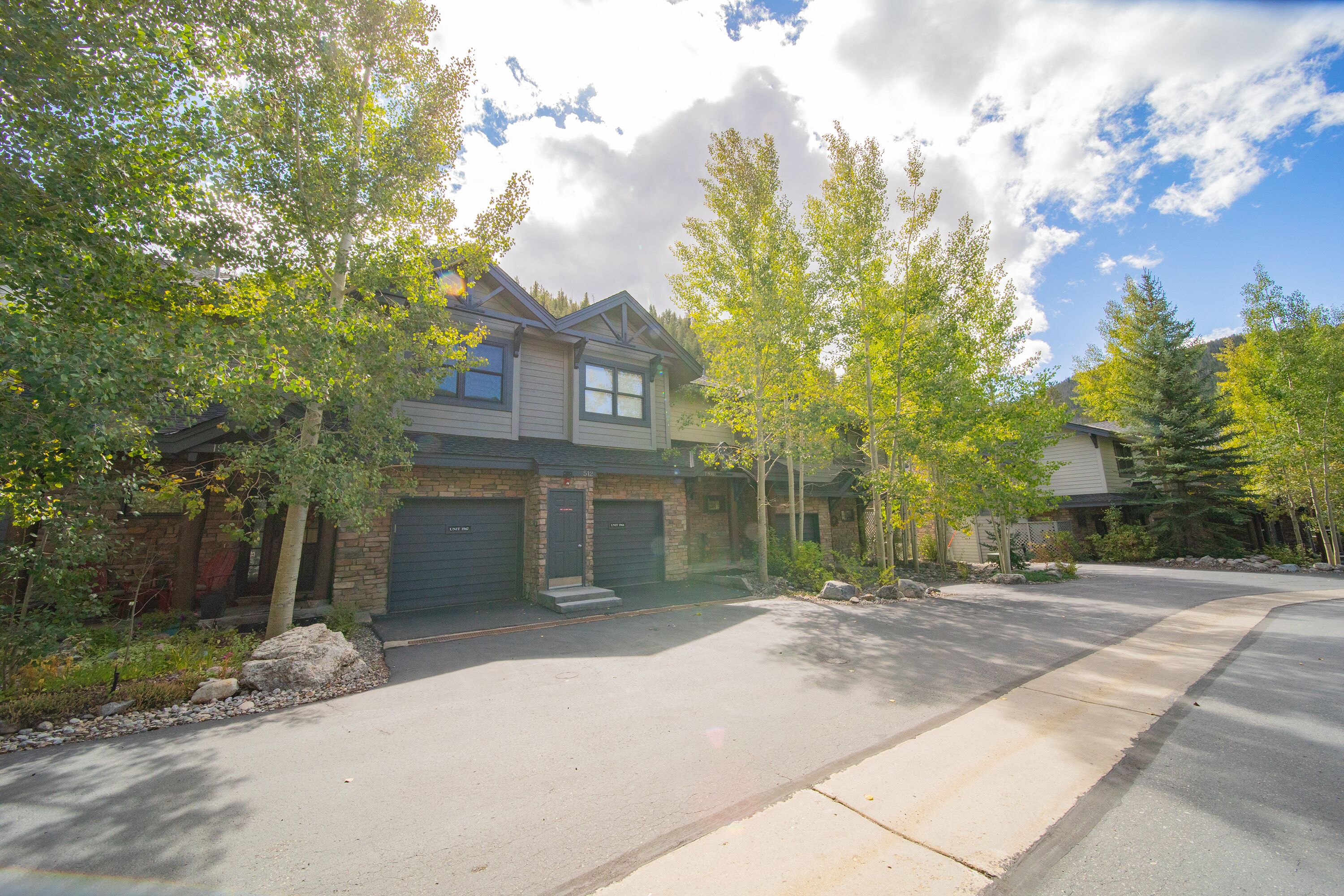 A residential house with a garage, driveway, and surrounding trees.