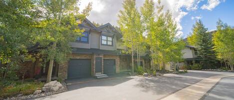 A residential house with a garage, driveway, and surrounding trees.