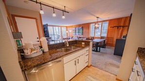 A modern kitchen with granite countertops, white cabinetry, and a built-in dishwasher. - Pines 2161 (Keystone)