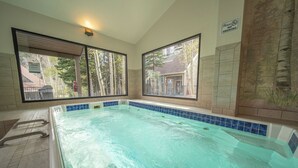 A swimming pool with clear water, a no-smoking sign, and windows with a view of trees and a building. - Pines 2161 (Keystone)