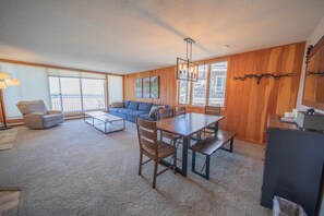A spacious living area with a sofa, a dining table, and a kitchen area. - Pines 2161 (Keystone)