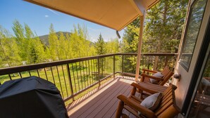 A wooden deck with a covered area, outdoor seating, and a view of a forested landscape. - Quicksilver 1621 (Keystone)