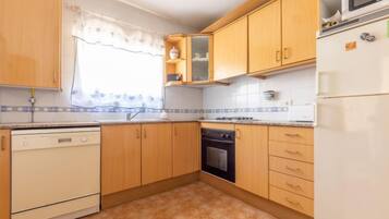 Een koelkast, een magnetron, een vaatwasser, kookgerei, borden en bestek