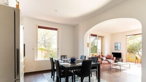 A spacious living area with a dining table, chairs, and a sofa. There is a television and a fireplace. - Apartment Grace by Interhome (Saint-Raphaël)