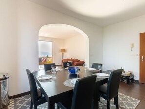 A dining area with a table set for four, a blue bowl, and a sofa in the background.