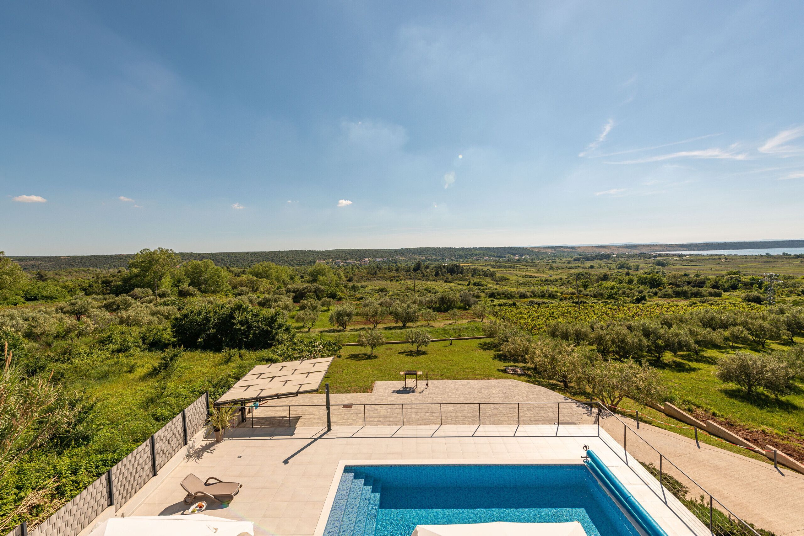 A swimming pool with a view of a green landscape and distant hills.