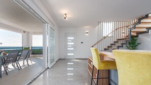 A modern interior with a staircase, a balcony with a table and chairs, and a view of the outdoors. - Villa Suton (Razanac)