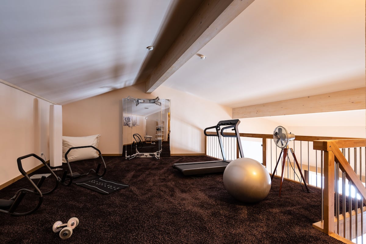 Een huisgymnasium met fitnessapparatuur, een loopband en een grote fitnessbal.