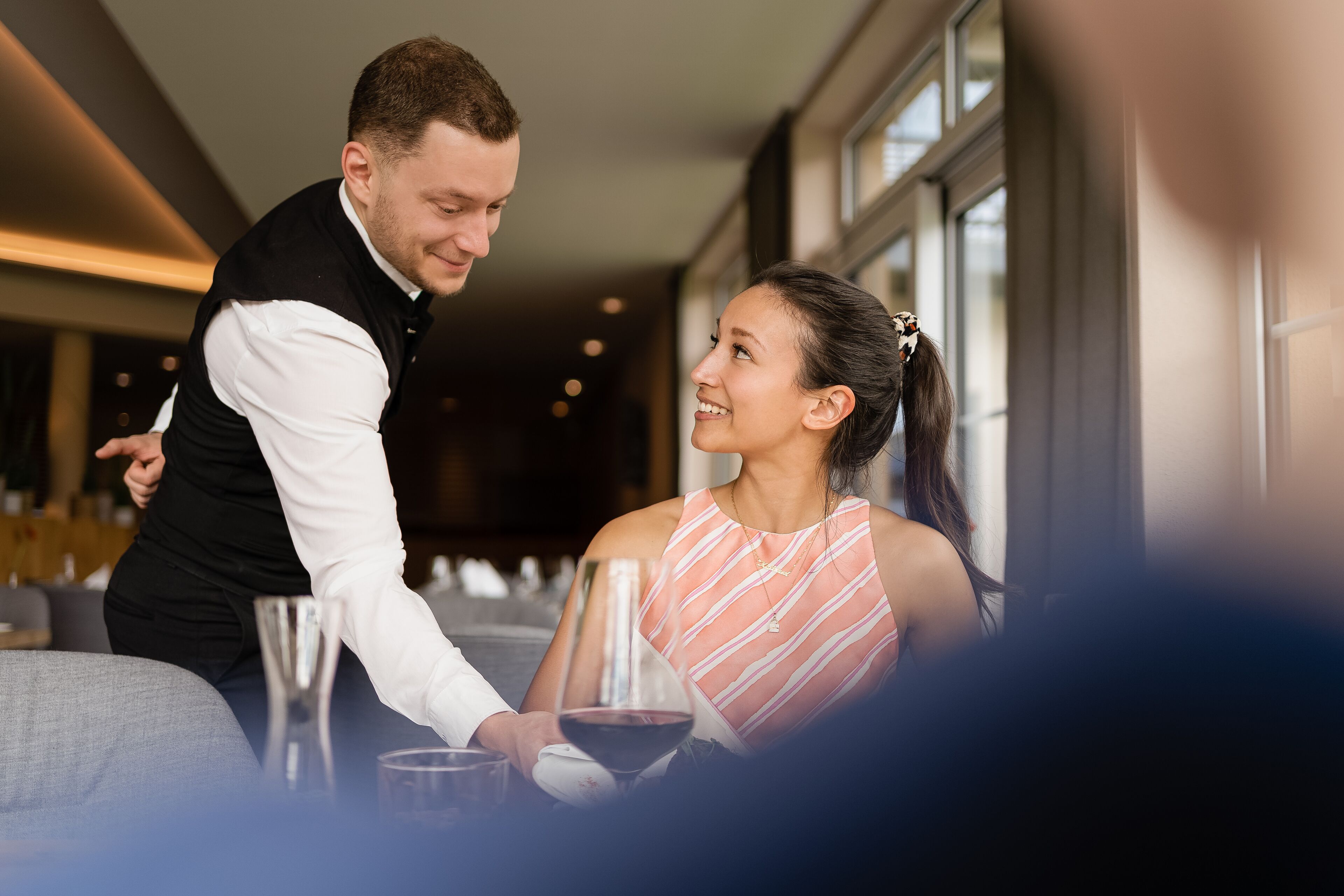 Un hombre sirve a una mujer en una mesa con copas de vino.